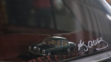 Close-up of a classic car model on display behind glass, featuring signature.