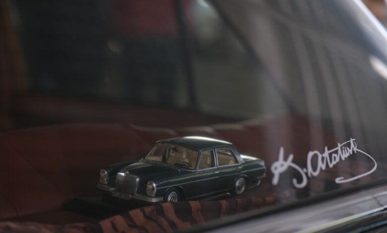 Close-up of a classic car model on display behind glass, featuring signature.