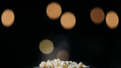 A close-up view of popcorn in a themed bucket with movie bokeh background.