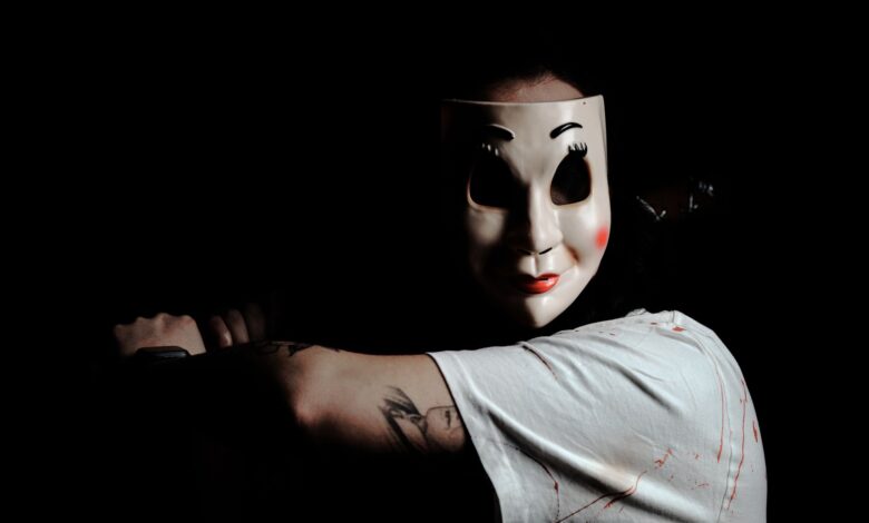 A mysterious figure wearing a mask creates a chilling atmosphere on a dark background.