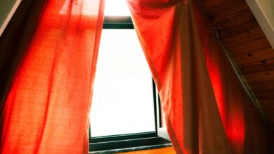 A cozy attic window with red curtains letting in warm sunlight, creating a serene indoor atmosphere.
