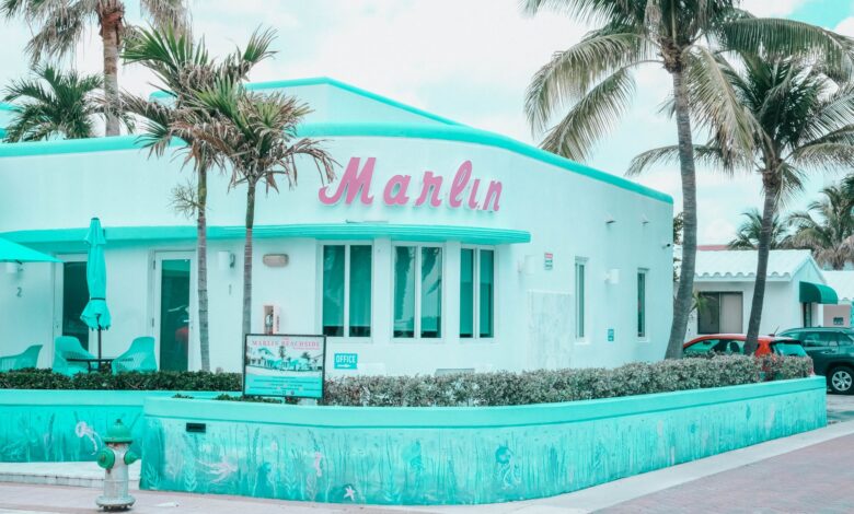 Explore the vibrant Art Deco architecture of Marlin Hotel in Hollywood, FL, with palm trees and a pastel palette.