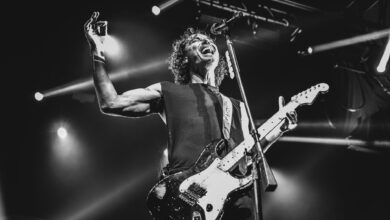 Black and white photo capturing an energetic guitarist performing live on stage.