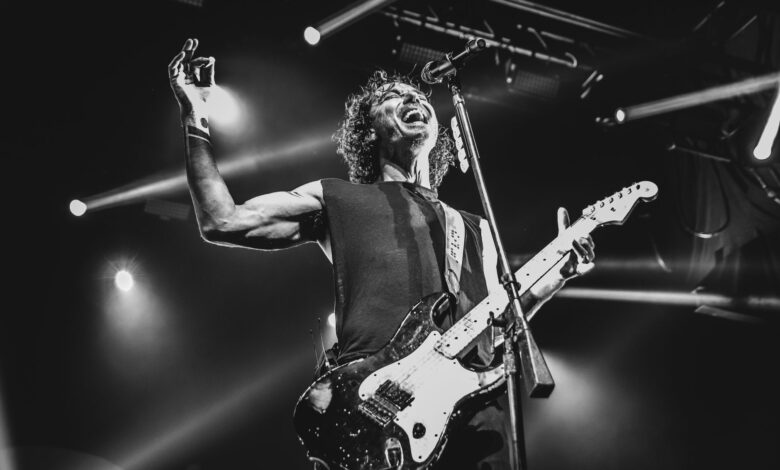 Black and white photo capturing an energetic guitarist performing live on stage.