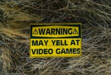 A funny yellow warning sign on grass reading 'Warning May Yell at Video Games'.