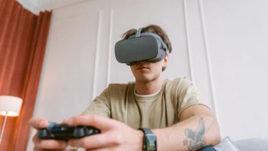 Adult male wearing a VR headset while intensely focused on playing a video game indoors.