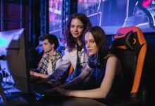 Three teenagers gaming intensely at an esports arena with computers and gaming chairs.
