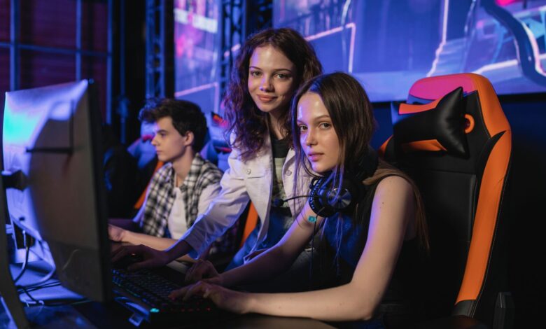 Three teenagers gaming intensely at an esports arena with computers and gaming chairs.