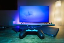 A stylish and ambient gaming setup featuring a controller, smart devices, and a TV in a lit living room.