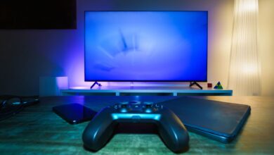 A stylish and ambient gaming setup featuring a controller, smart devices, and a TV in a lit living room.