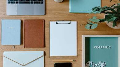 Stylish office supplies arranged neatly on a desk, including a laptop, clipboard, and notebooks.