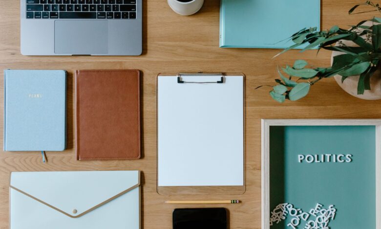 Stylish office supplies arranged neatly on a desk, including a laptop, clipboard, and notebooks.