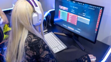 Young woman gaming at a PC high-tech setup, wearing headphones.
