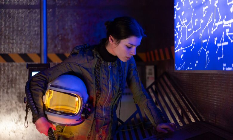 Woman astronaut in futuristic setting examining a digital star chart.