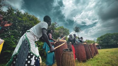 A group of people performing a traditional drumming ritual outdoors under a moody sky.