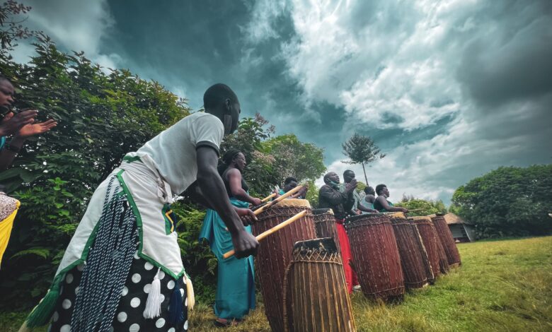 A group of people performing a traditional drumming ritual outdoors under a moody sky.
