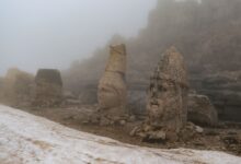 Mysterious ancient stone heads shrouded in fog at Mount Nemrut, Turkey.