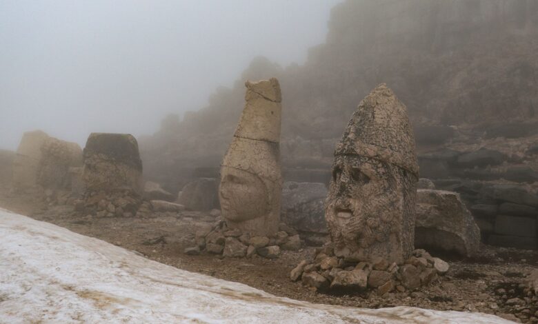 Mysterious ancient stone heads shrouded in fog at Mount Nemrut, Turkey.