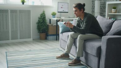 Smiling young man enjoying video games on a sofa at home.