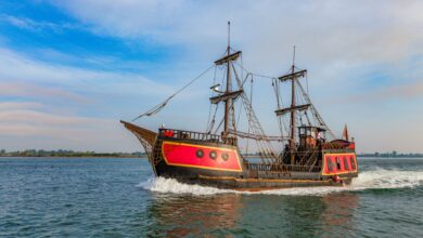 A vibrant pirate ship sails on a clear day, showcasing its vintage wooden structure and colorful design.