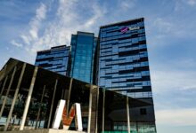Modern glass office building in Stockholm with Telia logo on a sunny day.