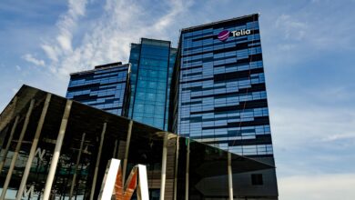 Modern glass office building in Stockholm with Telia logo on a sunny day.