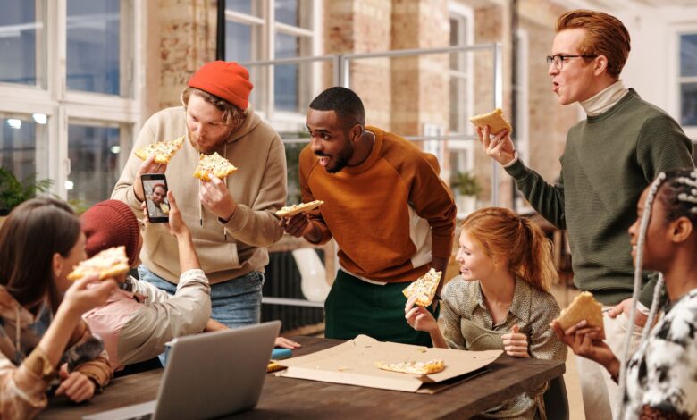 Colleagues having fun and eating pizza during an office break, capturing fun moments.