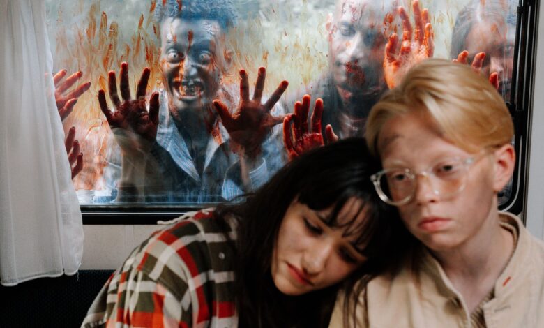 Frightened survivors hide inside while zombies approach the window.