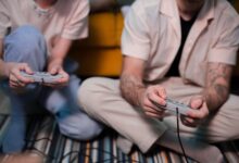 Two friends playing video games at home using retro controllers, enjoying a relaxing gaming session.