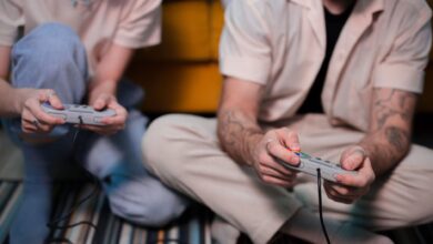 Two friends playing video games at home using retro controllers, enjoying a relaxing gaming session.