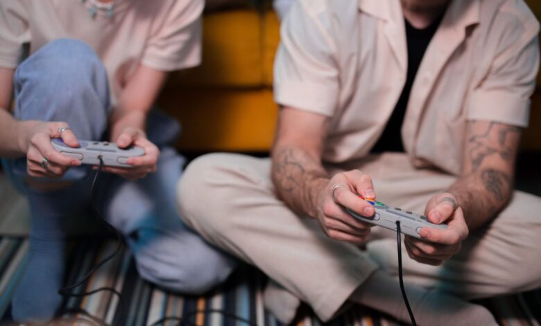Two friends playing video games at home using retro controllers, enjoying a relaxing gaming session.