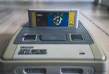 Vintage video game console with cassette with bright sticker on surface on wooden floor