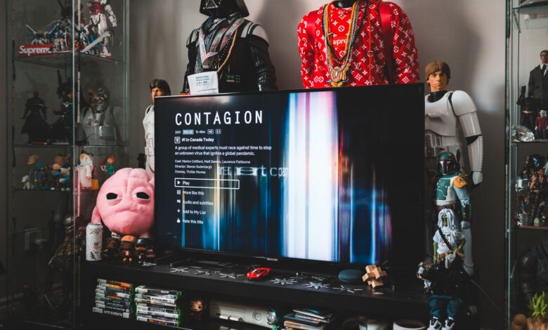 Desktop computer with creative video game on screen near assorted toy superheros on glass shelves in modern style apartment