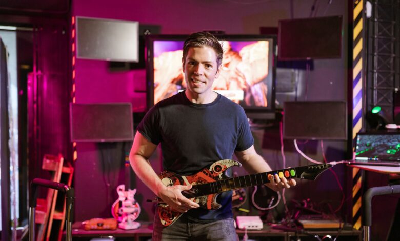 Adult male playing guitar controller in a vibrant gaming setup indoors, showcasing esports and recreation.
