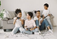 Four children playing video games together in a cozy living room setting.