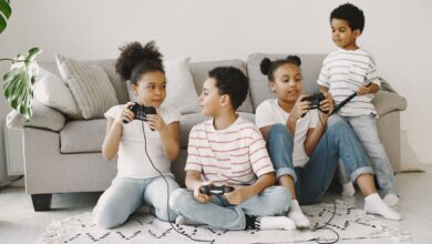 Four children playing video games together in a cozy living room setting.