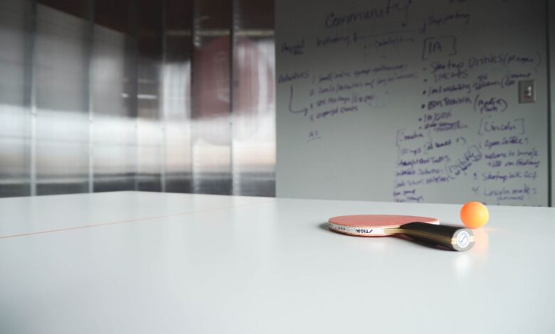 Close-up of ping pong paddle and ball on office table, creative workspace.
