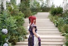 A woman in fantasy cosplay poses in a lush garden setting on stone steps, blending nature and creativity.