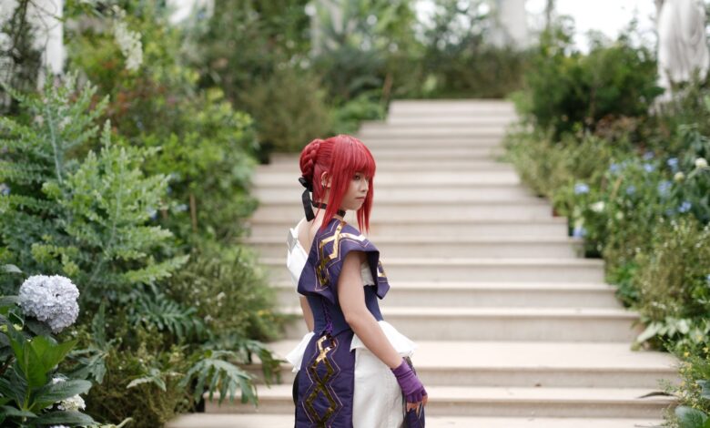 A woman in fantasy cosplay poses in a lush garden setting on stone steps, blending nature and creativity.