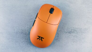 Orange computer mouse on a textured gray surface, showcased simply and artistically.