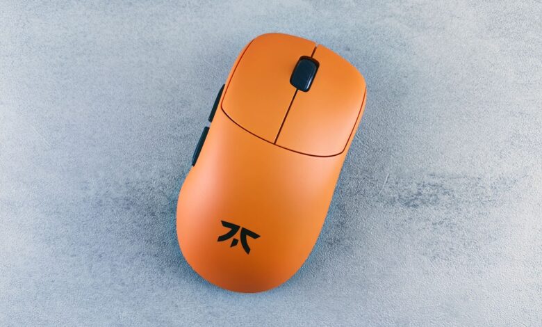 Orange computer mouse on a textured gray surface, showcased simply and artistically.
