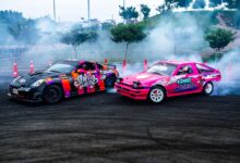 Dynamic scene of colorful drift cars racing on asphalt with smoke and fog in a racing area.