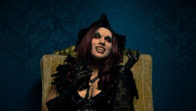 A dramatic portrait of a woman in vampire costume with gothic makeup and attire.