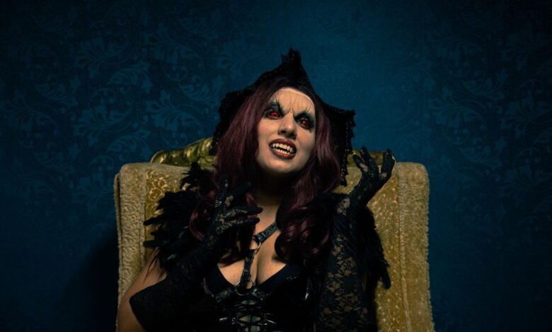 A dramatic portrait of a woman in vampire costume with gothic makeup and attire.