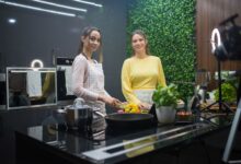 Two women cooking in a sleek kitchen with fresh ingredients and vibrant decor.