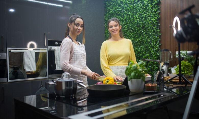 Two women cooking in a sleek kitchen with fresh ingredients and vibrant decor.