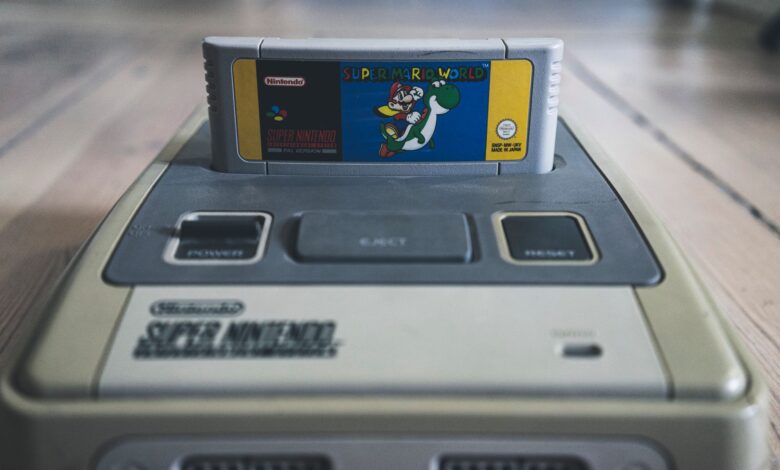 Vintage video game console with cassette with bright sticker on surface on wooden floor