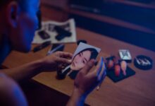 A person holds a photo in a dimly lit room, surrounded by objects suggesting mystery.
