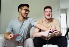 Two friends enjoying a video game session at home, smiling and sharing a fun moment together.