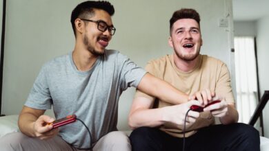 Two friends enjoying a video game session at home, smiling and sharing a fun moment together.